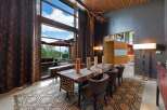 Experience luxurious dining with this stunning interior featuring a large wooden dining table set for six, adorned with a geometric runner and tall pillar candles.