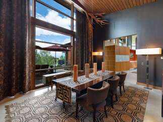 Experience luxurious dining with this stunning interior featuring a large wooden dining table set for six, adorned with a geometric runner and tall pillar candles.