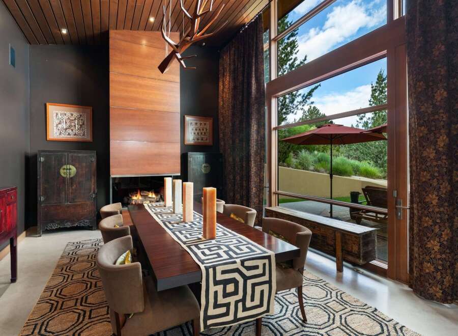 Experience luxurious dining in this elegant space featuring a grand fireplace and a large wooden dining table.
