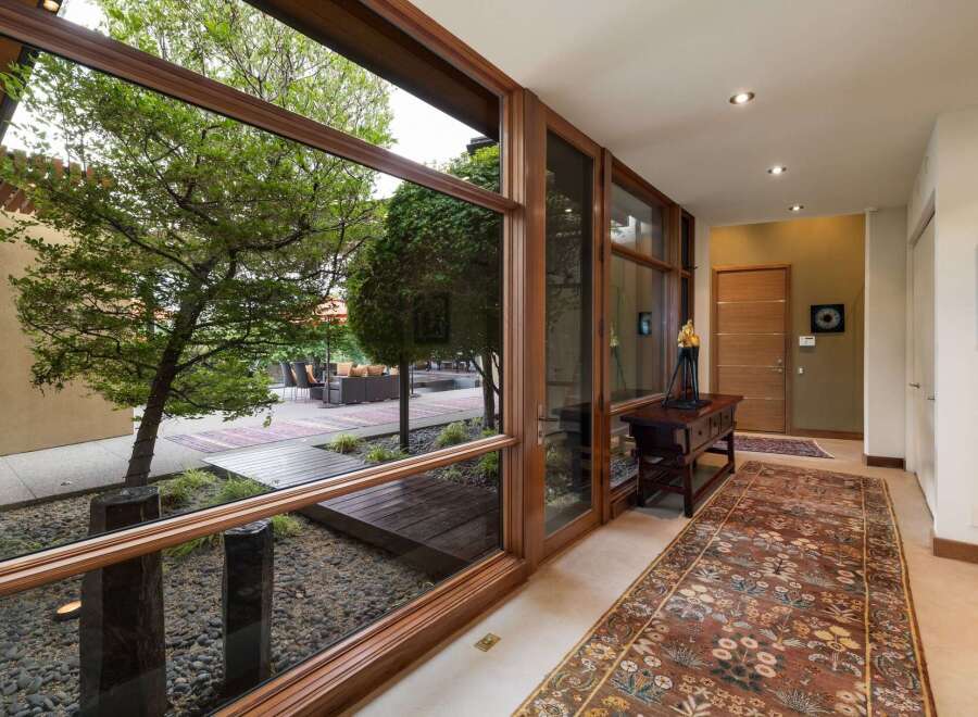 Experience seamless indoor-outdoor living with expansive floor-to-ceiling windows that frame lush garden views and a tranquil courtyard.