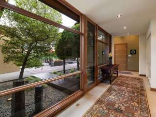 Experience seamless indoor-outdoor living with expansive floor-to-ceiling windows that frame lush garden views and a tranquil courtyard.