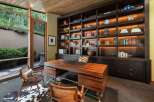 This luxurious home office features a stunning custom-built dark wood bookshelf with integrated lighting, showcasing a curated collection of books and decorative items.