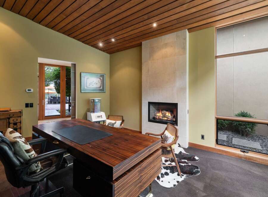 Experience luxury and comfort in this executive office, featuring a stunning wood-paneled ceiling and a modern gas fireplace.
