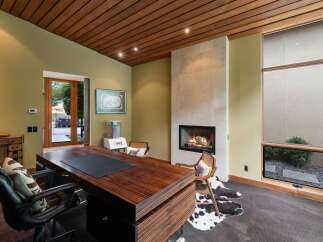 Experience luxury and comfort in this executive office, featuring a stunning wood-paneled ceiling and a modern gas fireplace.