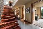 Experience modern luxury with this stunning staircase featuring rich wooden treads and sleek cable railings, illuminated by integrated lighting.