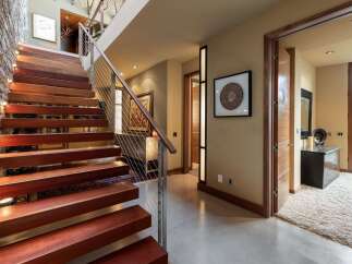 Experience modern luxury with this stunning staircase featuring rich wooden treads and sleek cable railings, illuminated by integrated lighting.