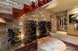 Discover this stunning wine cellar featuring a modern floating staircase with rich wooden treads and a sleek metal railing.