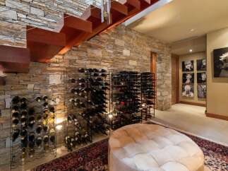 Discover this stunning wine cellar featuring a modern floating staircase with rich wooden treads and a sleek metal railing.