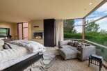 Experience luxury living in this master suite featuring a modern gas fireplace and expansive floor-to-ceiling windows that offer breathtaking views of the surrounding greenery.