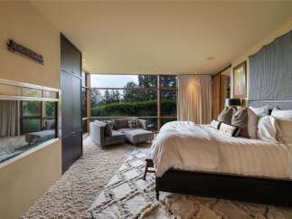 Experience luxury living in this master suite, featuring a plush, oversized rug and a comfortable sectional sofa perfect for relaxation.