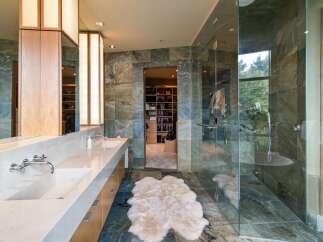 Experience luxury in this master bathroom featuring a spacious walk-in closet and a spa-like glass-enclosed shower.
