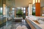 Experience luxury in this modern bathroom featuring a freestanding soaking tub with a stunning garden view through a large picture window.