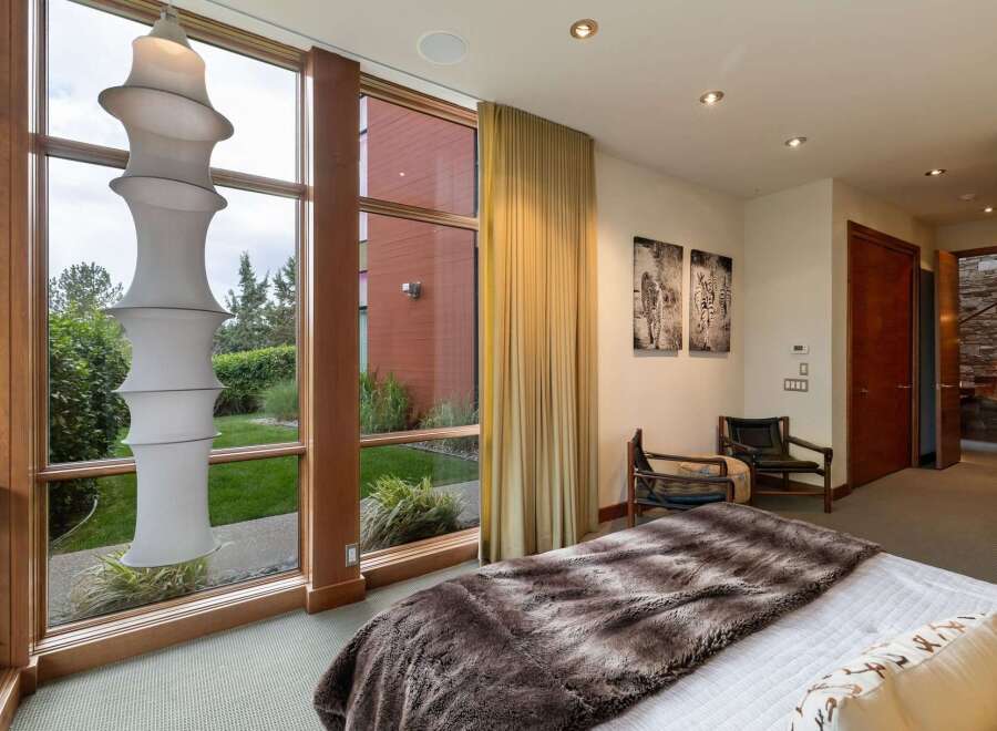 Experience luxurious living in this stunning bedroom featuring a large floor-to-ceiling window that floods the space with natural light and offers serene garden views.