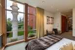 Experience luxurious living in this stunning bedroom featuring a large floor-to-ceiling window that floods the space with natural light and offers serene garden views.