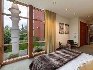 Experience luxurious living in this stunning bedroom featuring a large floor-to-ceiling window that floods the space with natural light and offers serene garden views.
