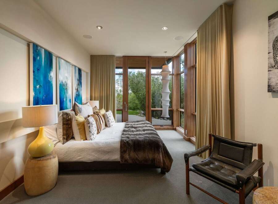 Experience luxury living in this master suite, featuring a plush king-size bed adorned with decorative pillows and a rich faux fur throw.