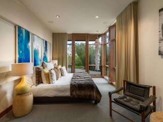 Experience luxury living in this master suite, featuring a plush king-size bed adorned with decorative pillows and a rich faux fur throw.