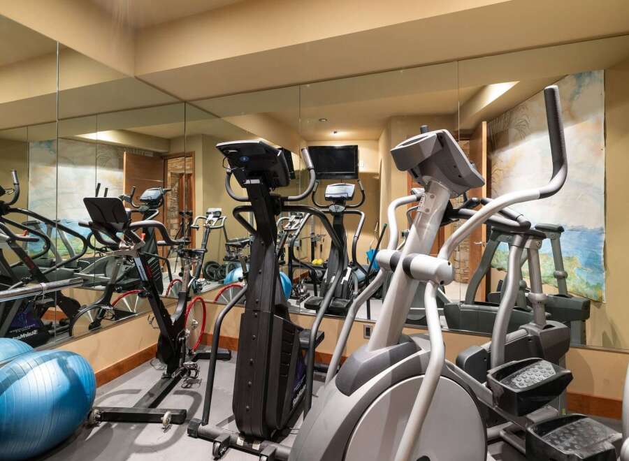 This home gym features a variety of cardio equipment, including ellipticals and stationary bikes, perfect for a full-body workout.