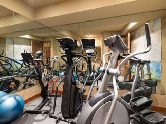 This home gym features a variety of cardio equipment, including ellipticals and stationary bikes, perfect for a full-body workout.