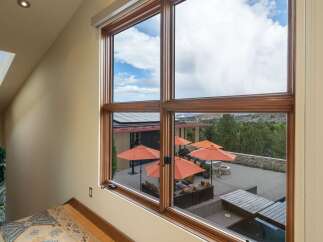 Expansive windows frame a stunning view of the outdoor living space, complete with multiple seating areas and vibrant orange umbrellas.