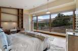 Experience breathtaking mountain views from this luxurious bedroom, featuring a spacious built-in desk and shelving unit perfect for a home office.