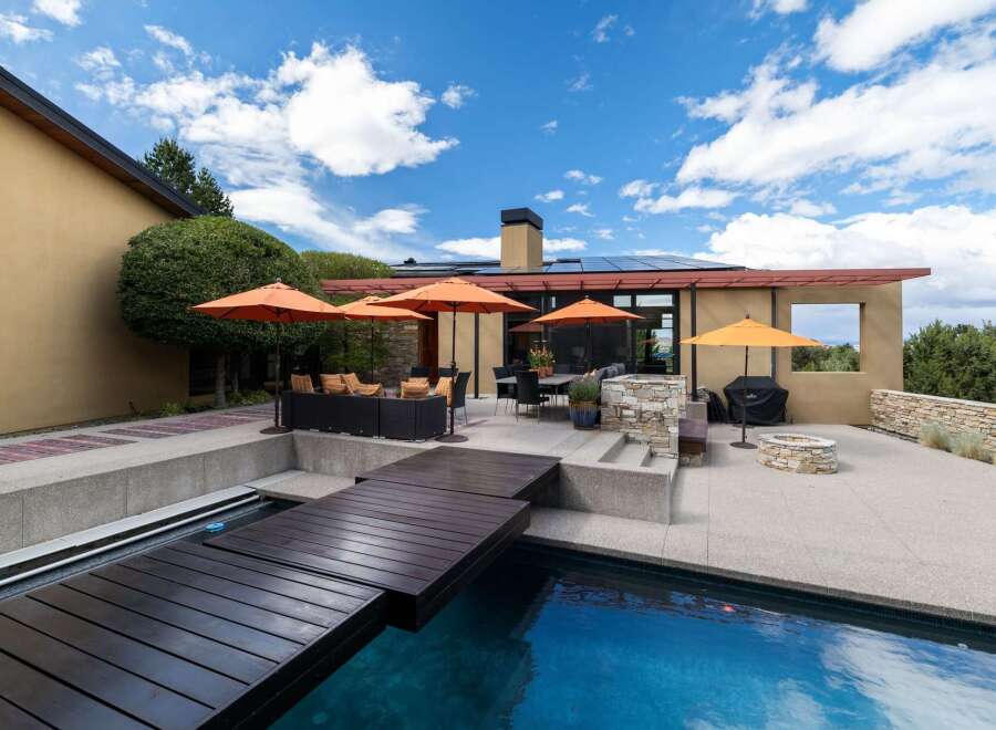 Experience luxury outdoor living with this stunning patio featuring a sparkling pool and a modern wooden deck.