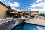 Experience luxury outdoor living with this stunning patio featuring a sparkling pool and a modern wooden deck.
