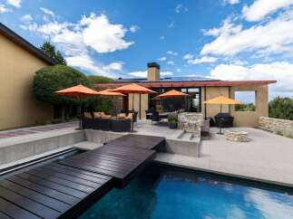 Experience luxury outdoor living with this stunning patio featuring a sparkling pool and a modern wooden deck.