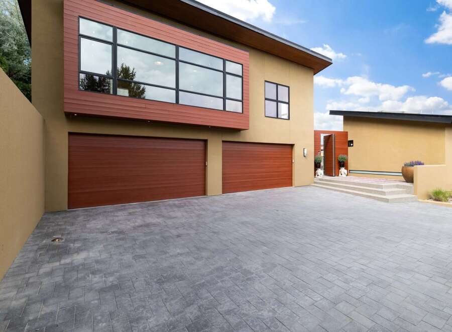 This modern home boasts a striking facade with warm wood accents and expansive windows, offering abundant natural light.