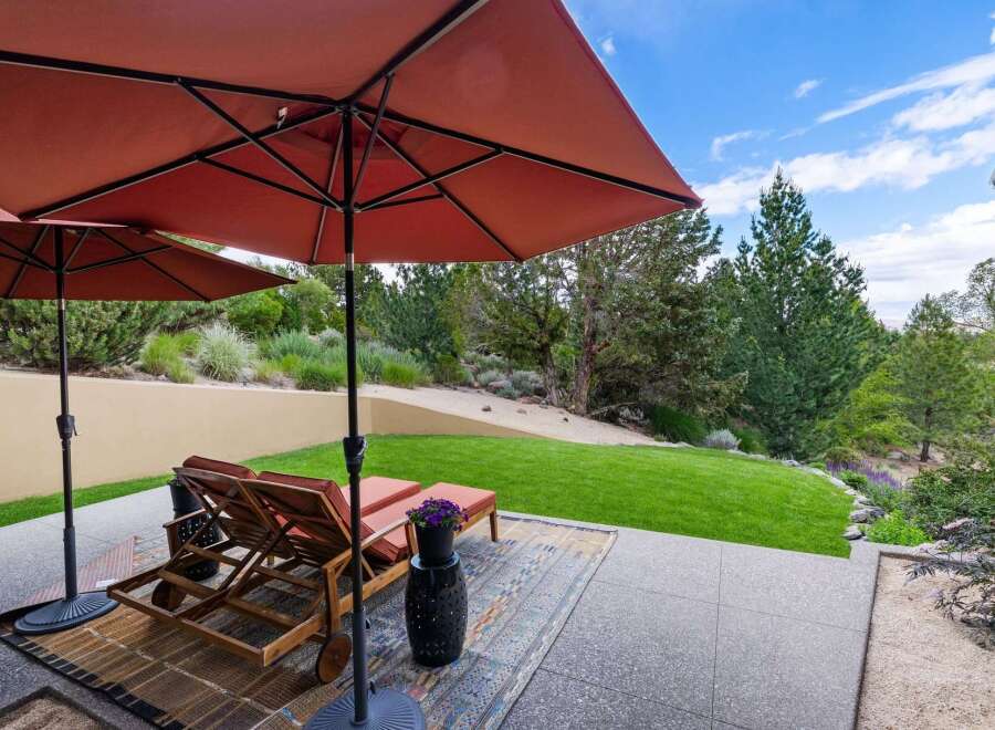 Enjoy outdoor living with this spacious patio featuring comfortable lounge chairs and large umbrellas for shade.