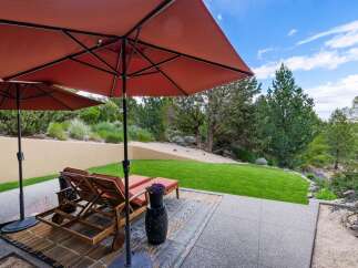 Enjoy outdoor living with this spacious patio featuring comfortable lounge chairs and large umbrellas for shade.