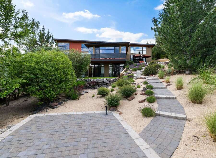 Discover this stunning modern home nestled on a hillside, featuring a unique architectural design with expansive windows offering panoramic views.