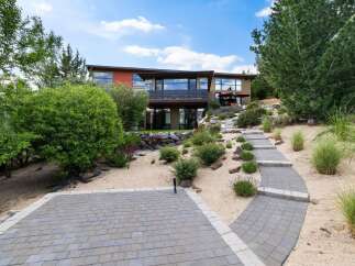 Discover this stunning modern home nestled on a hillside, featuring a unique architectural design with expansive windows offering panoramic views.