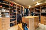 Step into this luxurious walk-in closet, meticulously organized with custom wood shelving and drawers.