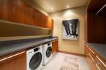 This modern laundry room features sleek cherry wood cabinetry and a durable gray countertop, providing ample storage and workspace.