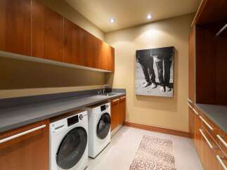 This modern laundry room features sleek cherry wood cabinetry and a durable gray countertop, providing ample storage and workspace.