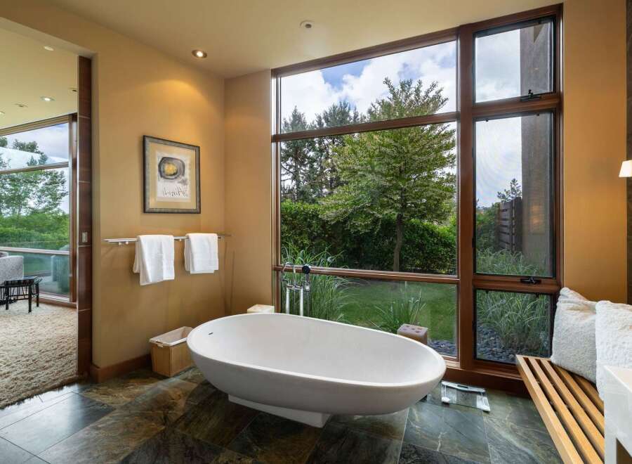 Experience ultimate relaxation in this luxurious bathroom, featuring a stunning freestanding bathtub with a picturesque view of the lush greenery outside.