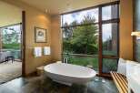 Experience ultimate relaxation in this luxurious bathroom, featuring a stunning freestanding bathtub with a picturesque view of the lush greenery outside.