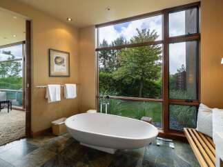 Experience ultimate relaxation in this luxurious bathroom, featuring a stunning freestanding bathtub with a picturesque view of the lush greenery outside.