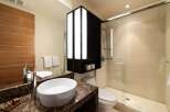 Experience modern luxury in this stunning bathroom featuring a sleek vessel sink atop a rich marble vanity.