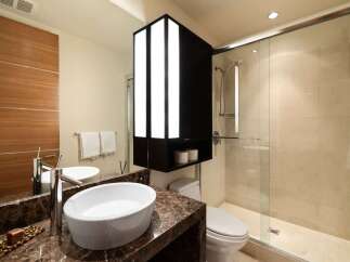 Experience modern luxury in this stunning bathroom featuring a sleek vessel sink atop a rich marble vanity.