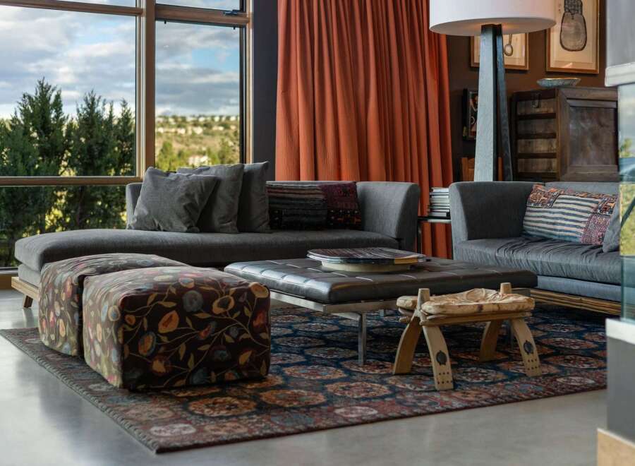 Experience luxurious living in this stunning living room, featuring a plush sectional sofa complemented by two patterned ottomans and a sleek leather coffee table.