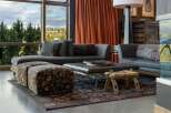 Experience luxurious living in this stunning living room, featuring a plush sectional sofa complemented by two patterned ottomans and a sleek leather coffee table.