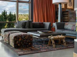 Experience luxurious living in this stunning living room, featuring a plush sectional sofa complemented by two patterned ottomans and a sleek leather coffee table.