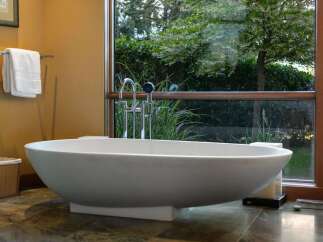 Indulge in ultimate relaxation in this luxurious bathroom, featuring a stunning freestanding bathtub positioned to offer serene garden views.