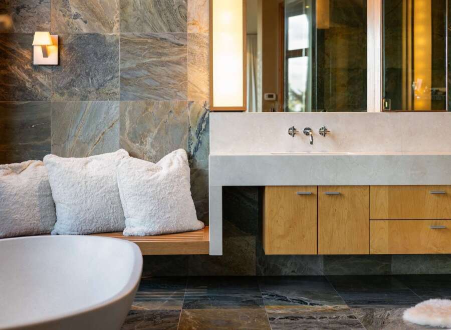 Experience luxury in this modern bathroom featuring a freestanding bathtub and a sleek vanity with a stone countertop.