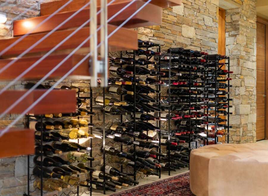 Experience luxury living with this stunning wine cellar, featuring a vast collection of wine bottles neatly organized on sleek metal racks.