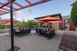 Experience luxurious outdoor living with this stunning patio featuring a spacious dining area under a pergola and a comfortable lounge space with orange umbrellas for shade.
