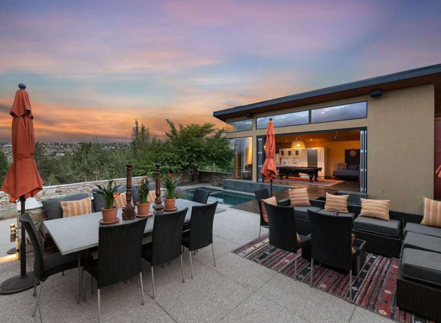 Experience luxurious outdoor living with this stunning patio featuring a dining set, lounge area, and a sparkling pool.