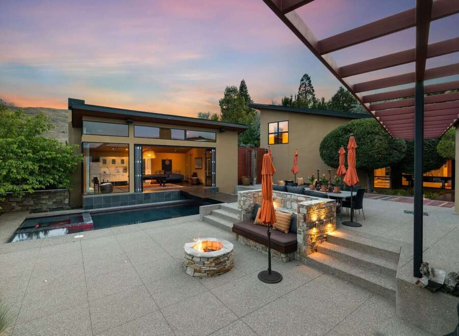 Experience luxury outdoor living with this stunning backyard oasis, featuring a modern pool and spa, a cozy fire pit, and a spacious patio perfect for entertaining.